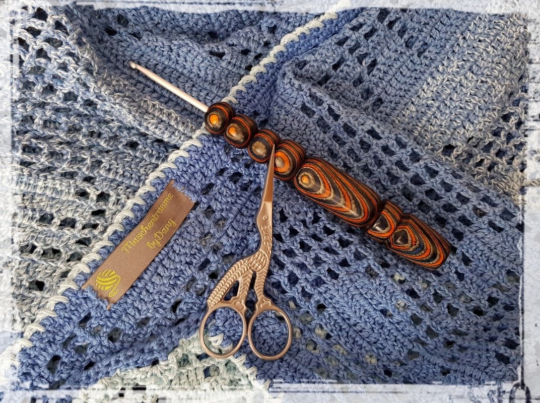 Blaues gehäkeltes Dreieckstuch mit Lochmuster, Häkelnadel und Zierschere