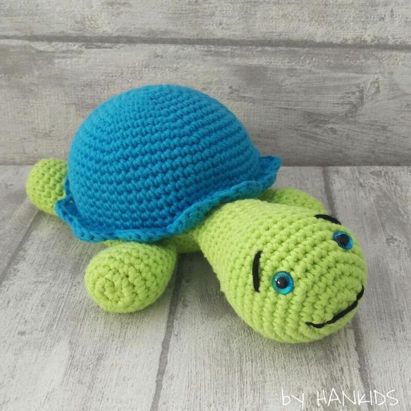 Lime green crocheted amigurumi turtle with bright blue shell on wooden surface