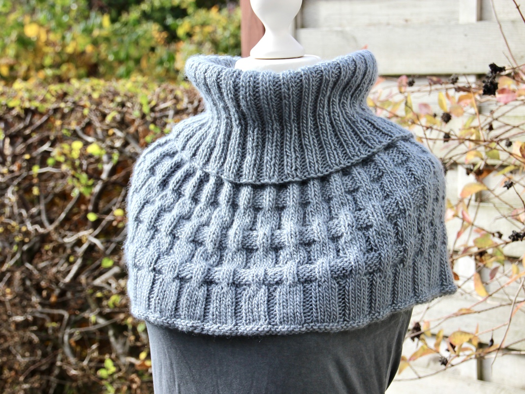 Light blue-grey knitted collar scarf on a mannequin with a tall ribbed collar and basketweave texture.