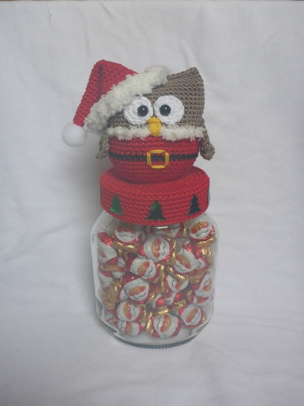 Gehäkelte Eule in rotem Weihnachtskostüm auf einem Glas mit Schokoladenkugeln