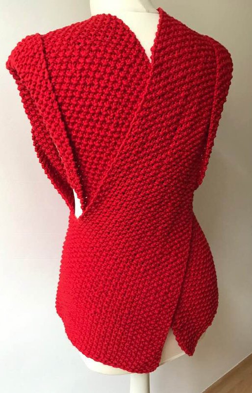 Rote gestrickte Überwurfweste mit dichtem Strukturmuster auf Schneiderpuppe