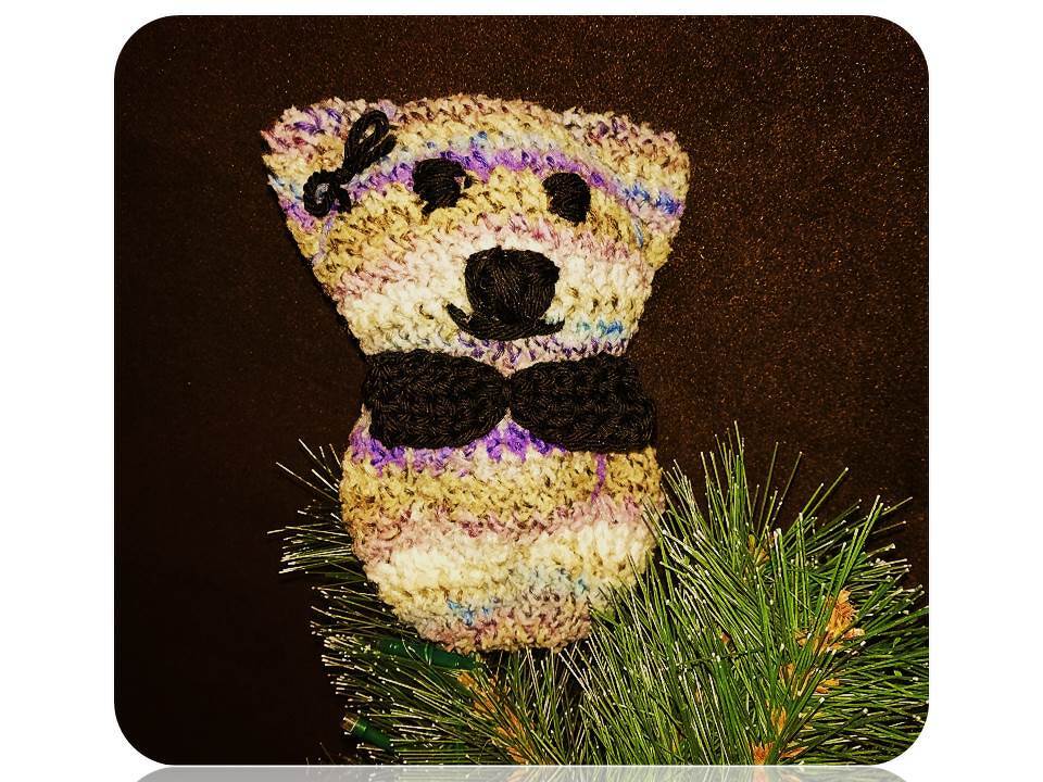 Kompakter gehäkelter Amigurumi-Teddy aus mehrfarbigem Pastellgarn mit gestickter Nase und schwarzer Fliege