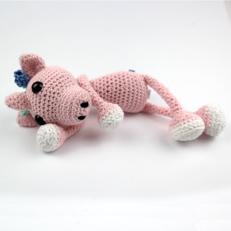 Rosa gehäkeltes Amigurumi-Tier liegend mit langen Beinen und weißen Pfoten