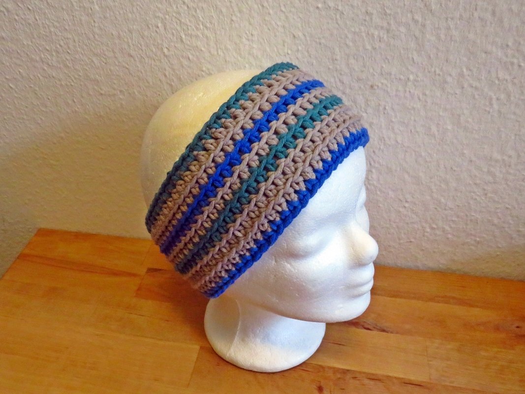 Gehäkeltes Stirnband in Blau, Petrol und Beige auf einem weißen Mannequinkopf