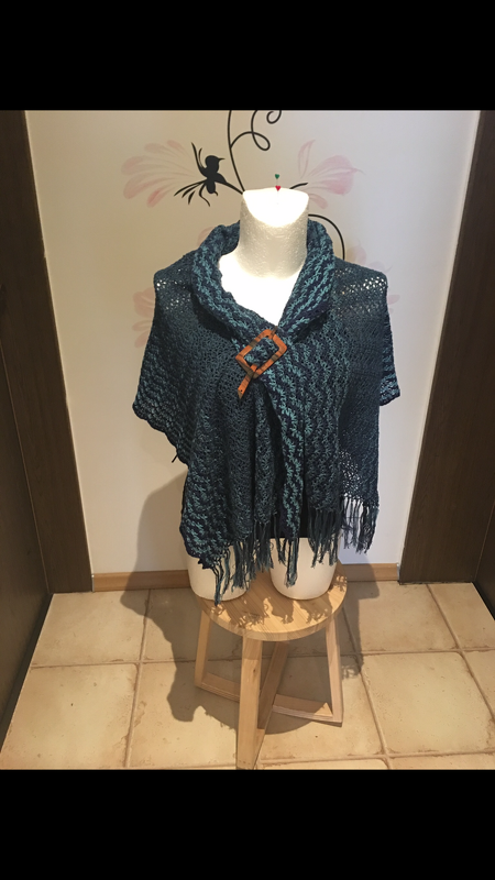Gehäkelter Poncho in Petrol/Blaugrün mit Wellenmuster, Fransen und brauner Schnalle auf Schneiderpuppe