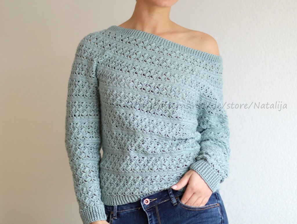 Frau trägt hellmintfarbenen, gehäkelten Off-Shoulder-Pullover mit Lochmuster und gerippten Bündchen