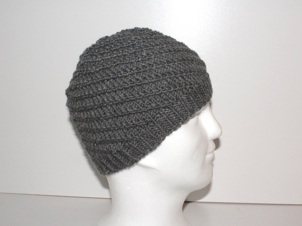 Seitliche Ansicht einer grauen gestrickten Beanie mit diagonaler Struktur auf einem weißen Schaufensterkopf