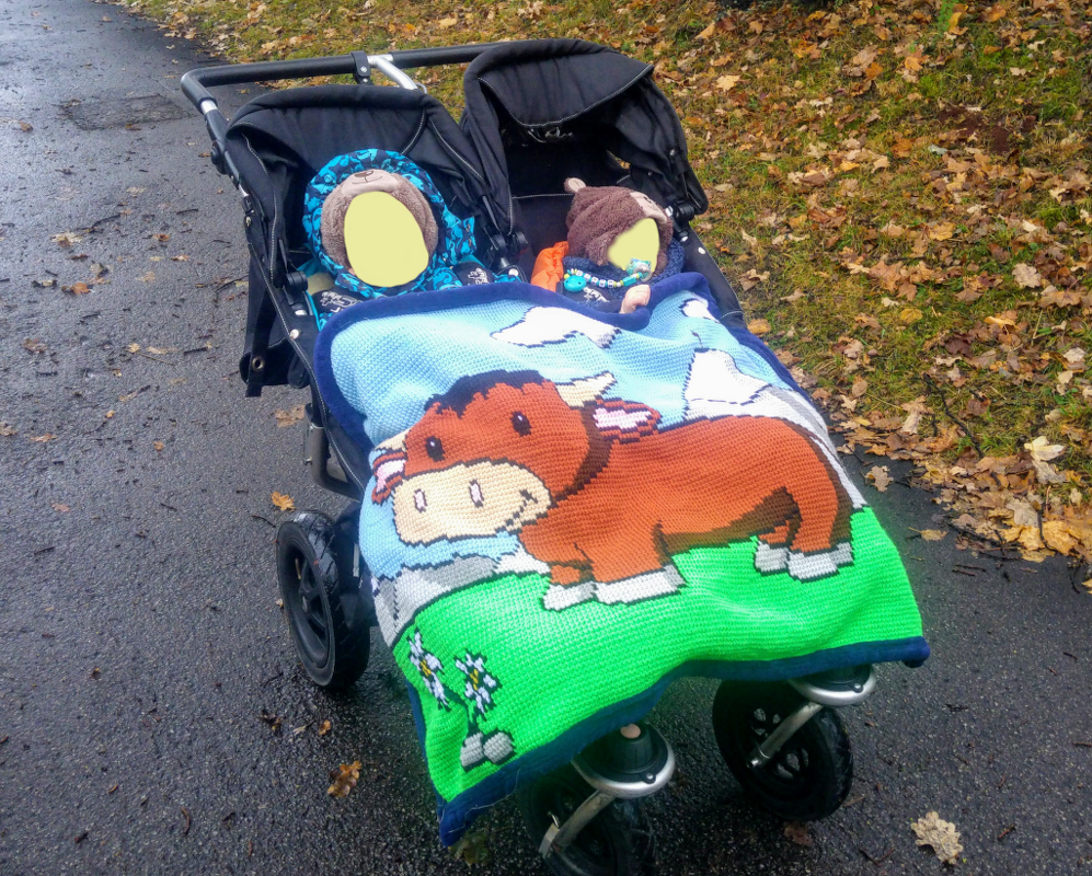 Zwillingskinderwagen mit gehäkelter Pixeldecke mit großem Kuhmotiv
