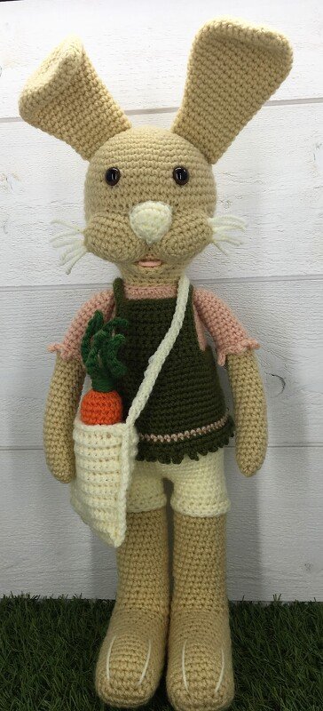 Gehäkelter beiger Amigurumi-Hase mit grünem Latzkleid und Umhängetasche mit Möhre