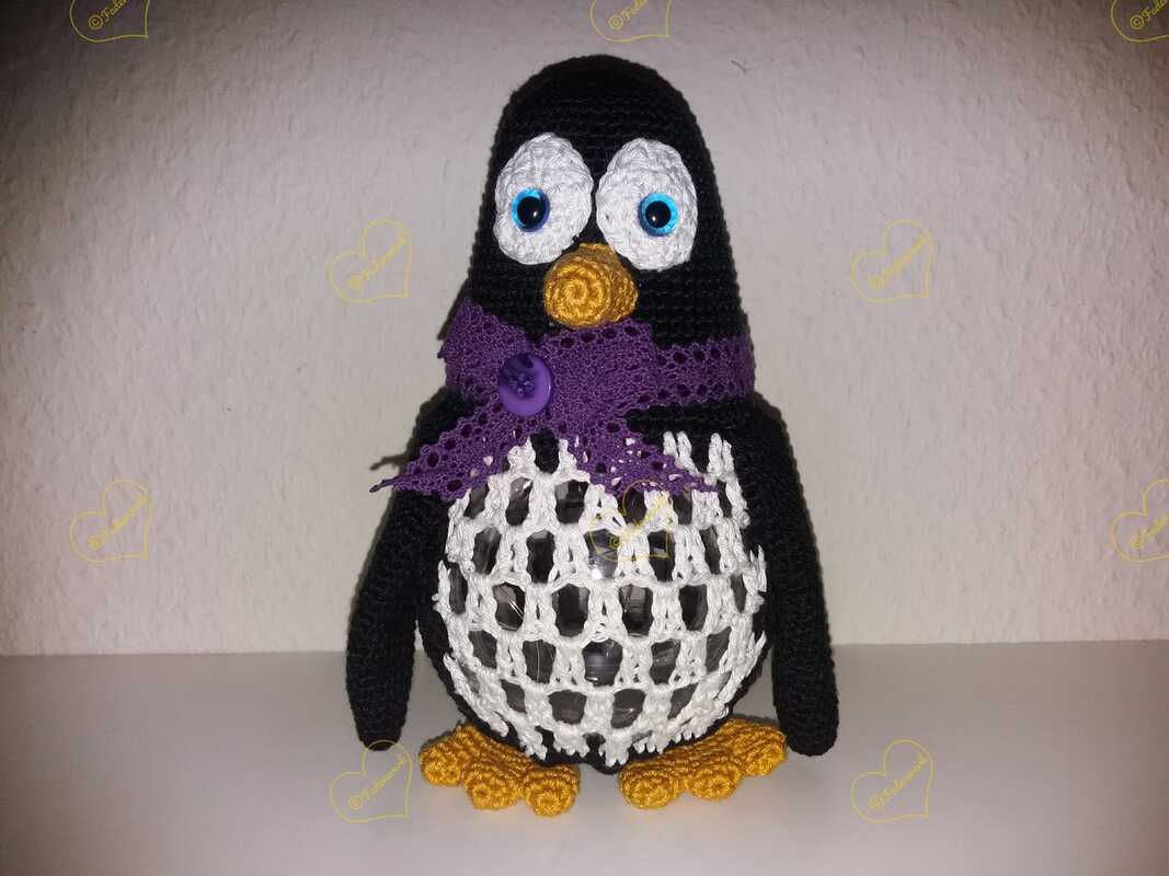 Gehäkelter Pinguin mit lila Schal, Netzmuster am Bauch und orangefarbenem Schnabel und Füßen