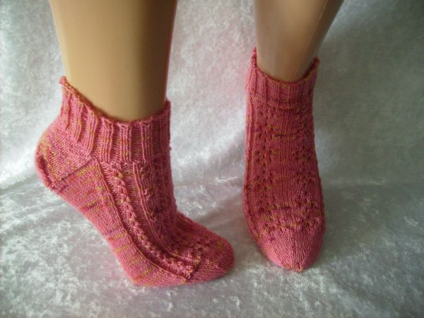 Rosa gestrickte Knöchelsocken mit Rippenbund und Lochmuster an Schaufensterpuppenbeinen