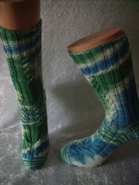 Paar gestrickter blau-grüner Kniestrümpfe mit Zopfmuster auf Schaufensterfüßen