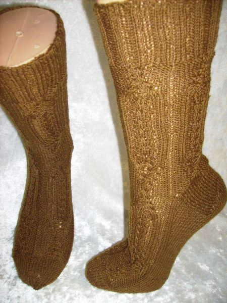 Zwei braune handgestrickte Socken mit Rippen- und Strukturmuster; eine flach liegend, eine auf Schuhform
