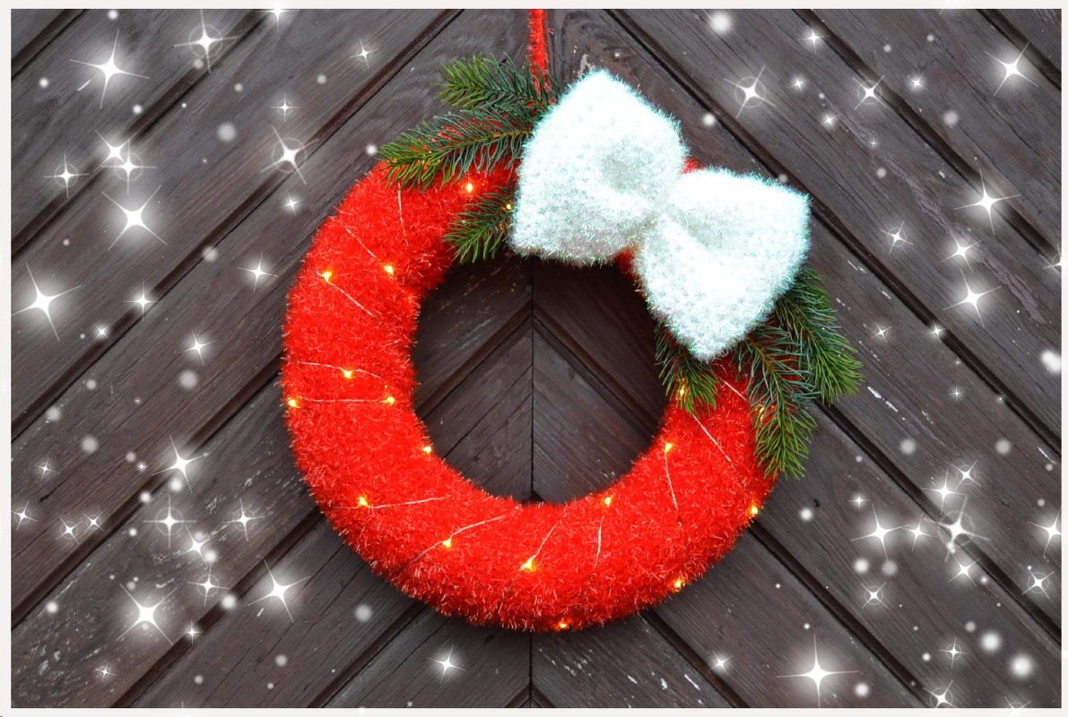 Roter gehäkelter Weihnachtskranz mit weißer Schleife an dunkler Holztür
