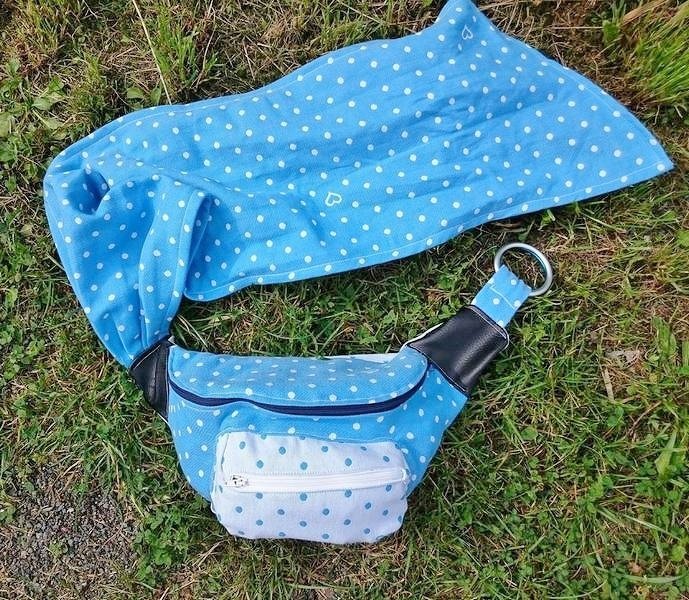 Hellblaue Bauchtasche mit weißen Punkten auf Gras