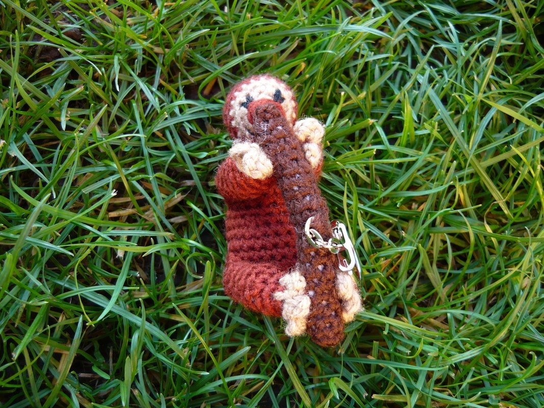 Gehäkelter Schnabeltier-Schlüsselanhänger mit Baumstamm auf Gras