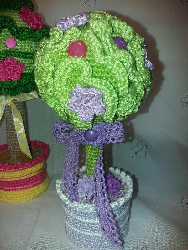 Gehäkeltes Topiary: grüne Kugel mit lila Blüten, Spitzenband und gestreiftem Topf