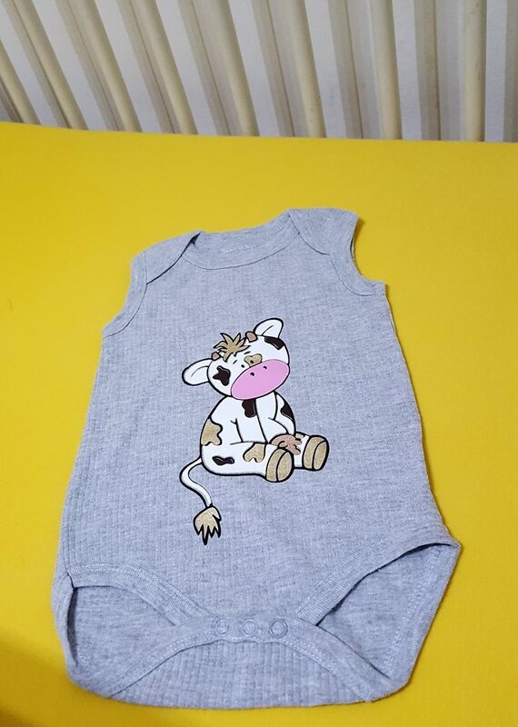 hellgrauer Babybody mit klar konturiertem Kuh-Plotmotiv und separaten Farbflächen