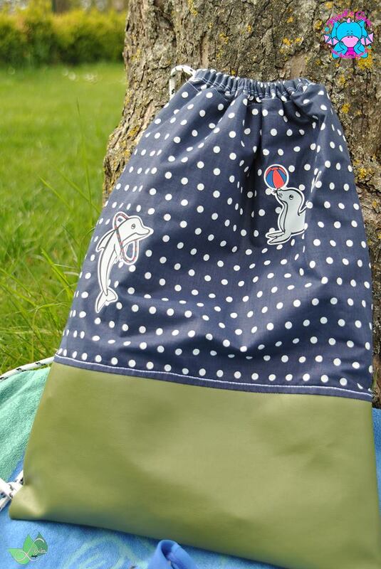 Dunkelblauer, weiß gepunkteter Turnbeutel mit olivgrünem Boden und Plotmotiven von Delfin und Seehund