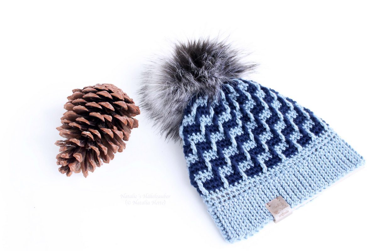 Gehäkelte Wintermütze in Dunkel- und Hellblau mit grauem Bommel und Tannenzapfen