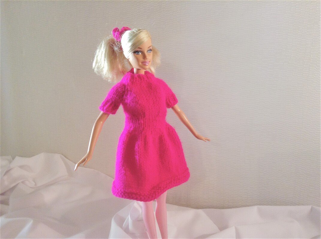 Stehende Spielpuppe mit schlichtem, gestricktem pinkem Kleid