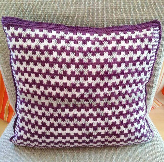 Quadratisches gestricktes Kissen mit lila-weißem Hahnentrittmuster auf beigem Sessel