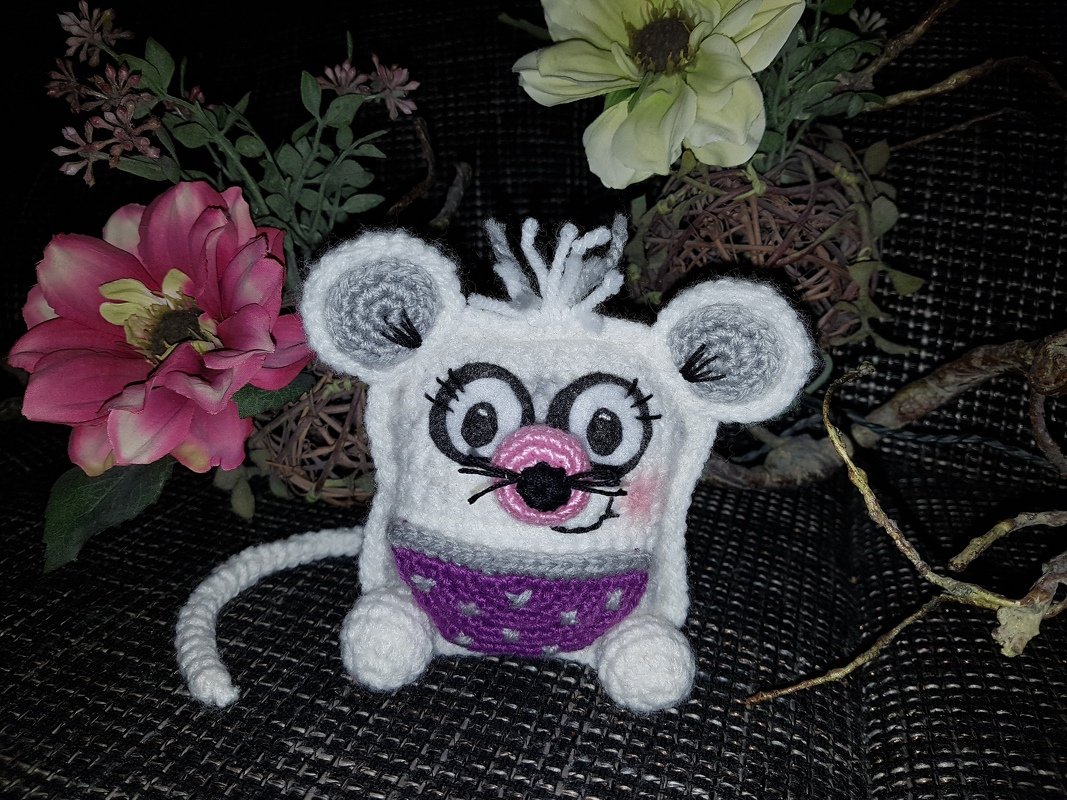 Gehäkelte Amigurumi-Maus in Weiß und Lila mit großen Augen und rosa Nase.