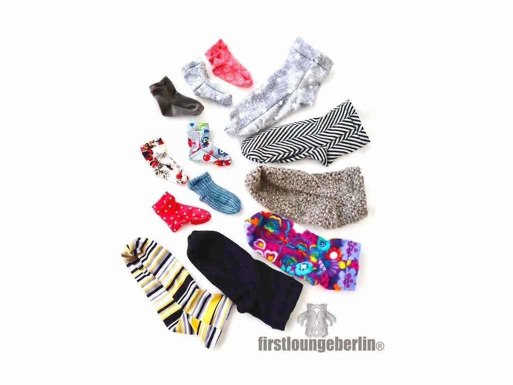 Bunte gemusterte Socken und Stulpen verschiedener Größen auf weißem Hintergrund