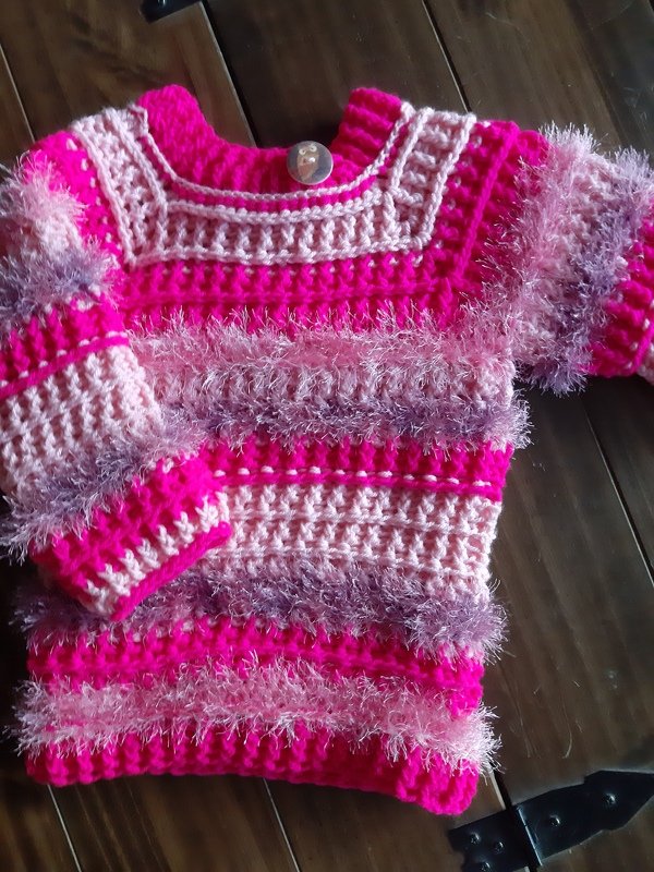 Gehäkelter gestreifter Kinderpullover in Pink und Rosa mit flauschigen Streifen und Knopf am Kragen