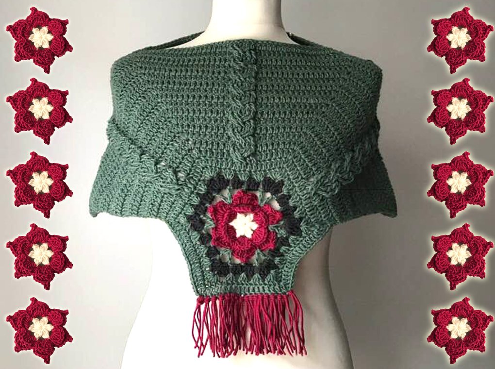 Salbeigrüner gehäkelter Poncho mit zentraler Blumenapplikation in Rot und Creme sowie roten Fransen