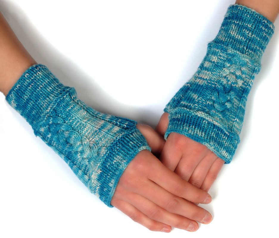Blau-melierte gestrickte Armstulpen mit Zopfmuster an zwei Händen vor hellem Hintergrund