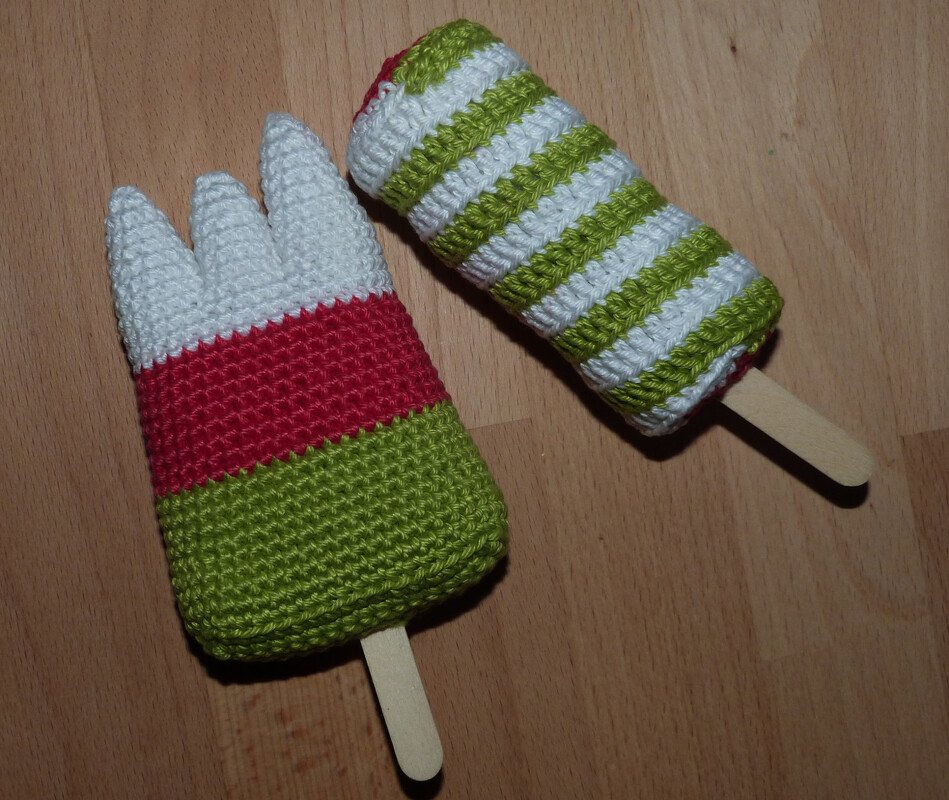 Zwei gehäkelte Eis am Stiel in Grün, Weiß und Rot auf Holzuntergrund