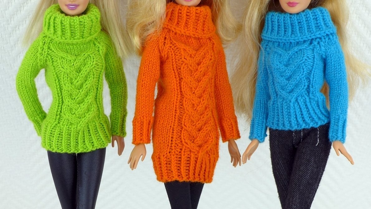 Drei Puppen in grünen, orangen und blauen gestrickten Pullovern mit zentralem Zopfmuster und verschiedenen Kragenformen