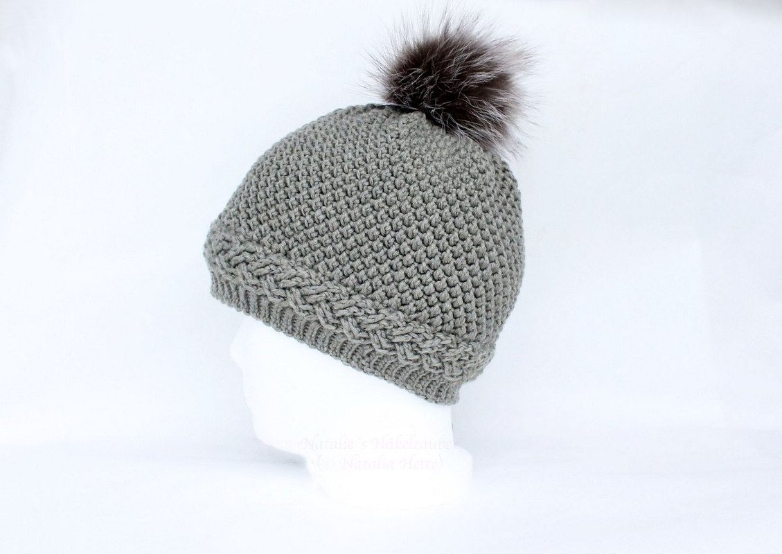 Gehäkelte graue Mütze mit Zopfmuster und dunklem, flauschigem Bommel