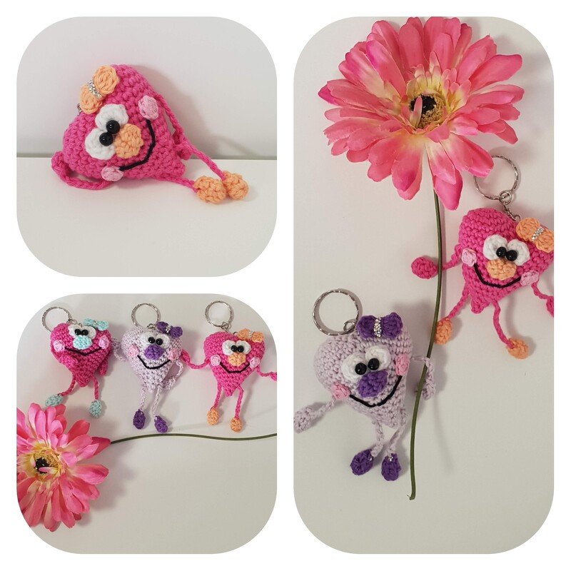 Mehrere gehäkelte Herz-Schlüsselanhänger in Rosa und Lila mit lachenden Gesichtern und kleinen Schleifen