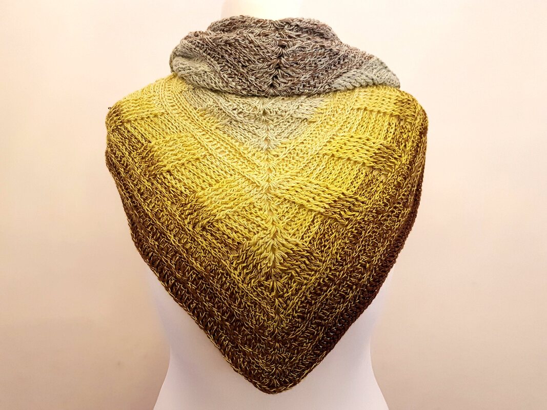 Gehäkeltes Dreieckstuch auf einer Schneiderpuppe, Farbverlauf von Gelb zu Braun, strukturiertes Muster