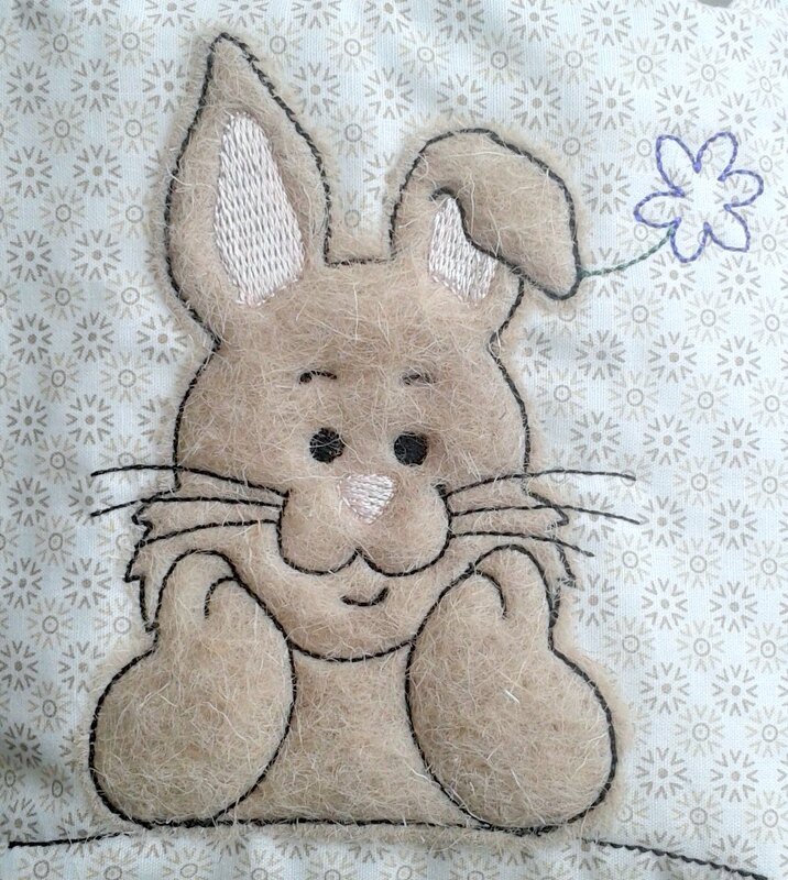 Gestickter Osterhase als filzartige Applikation mit schwarzer Kontur auf hellgemustertem Stoff