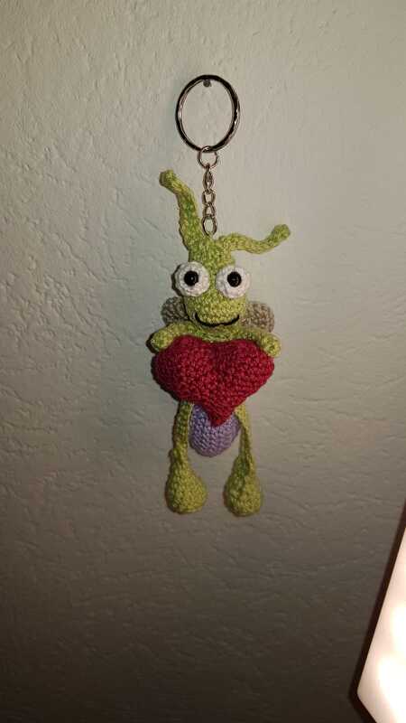 Verspielte handgehäkelte grüne Amigurumi-Figur mit rotem Herz an Schlüsselring