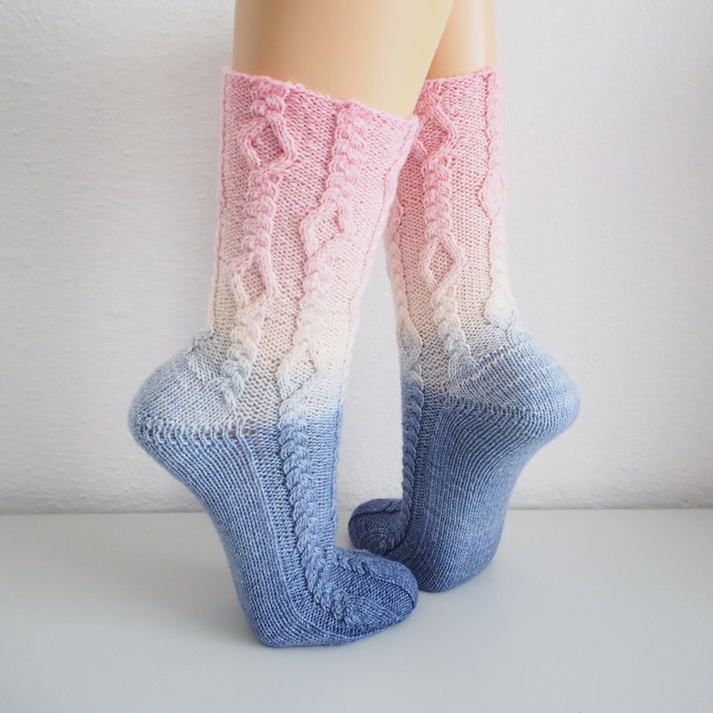 Calf-length knitted socks with pink-to-blue gradient and braided cable stitch