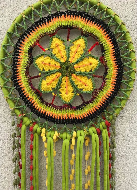 Rundes gehäkeltes Mandala-Traumfänger mit gelber Blumenmitte, orange-grünen Runden und langen grünen Fransen