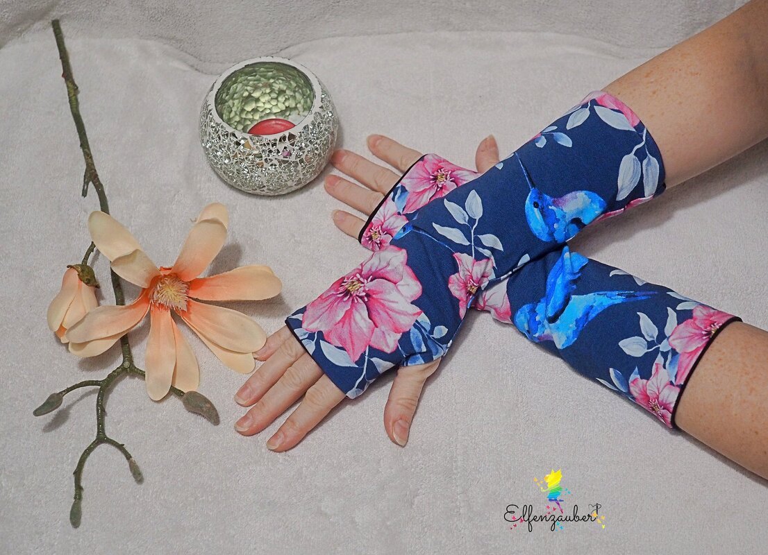 Blaue, fingerlose Armstulpen mit rosa Blumen und Kolibri-Motiv an den Händen