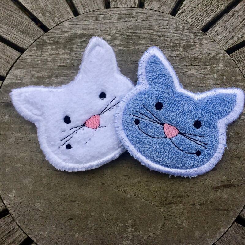 ITH Katzenkopf-Applikationen in Weiß und Hellblau, gestickt, auf Holzfläche