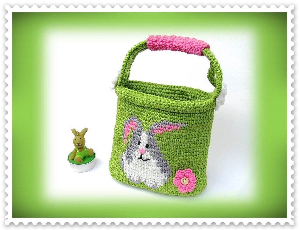 Grünes gehäkeltes Ostertäschchen mit Hasenintarsia, Henkel mit pinker Polsterung und rosa Blüte mit Knopf