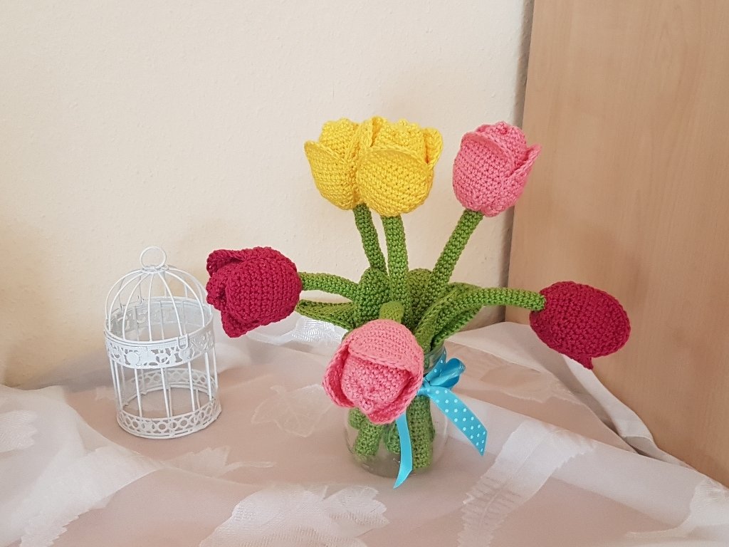 Gehäkelte Tulpen in Glasvase mit blauem Band und weißem Deko-Käfig