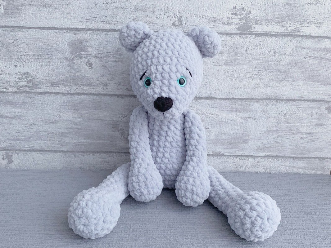 hellgrauer gehäkelter Amigurumi-Teddybär sitzend mit türkisfarbenen Augen