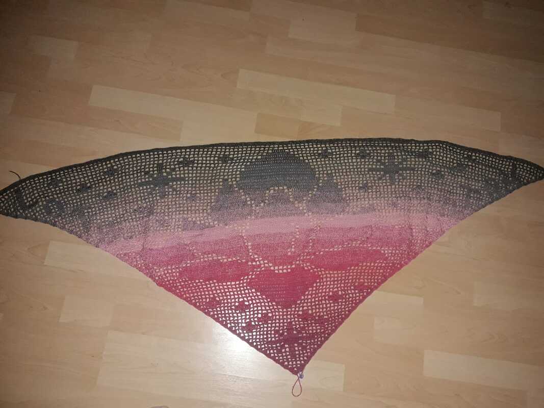 Gehäkeltes Dreieckstuch in Grau und Rosa mit offenem Lochmuster auf hellem Boden