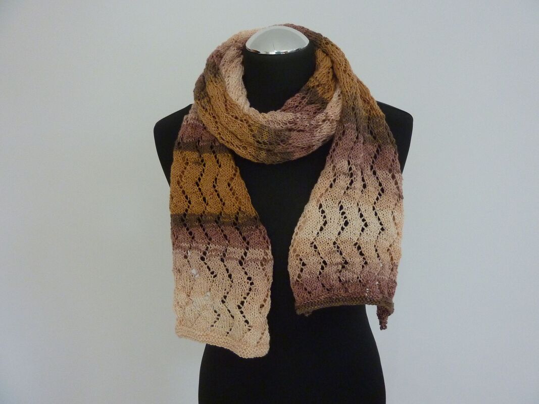 Gestrickter Schal mit Ajourmuster und sanftem Farbverlauf an einer schwarzen Schaufensterpuppe