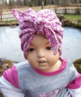 Kinderpuppe mit rosa-lila gehäkeltem Turban und Knoten vorne
