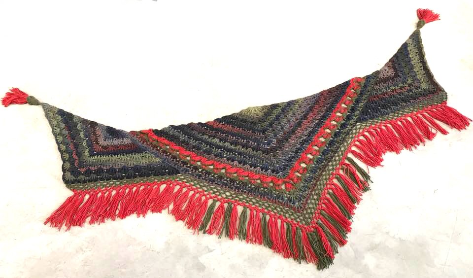 Gehäkeltes Dreieckstuch mit roten Fransen und Quasten
