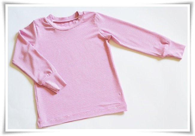 Pink-weiß gestreiftes Kinder-Langarmshirt mit Rundhalsausschnitt und Bündchen, flach auf weißem Untergrund.